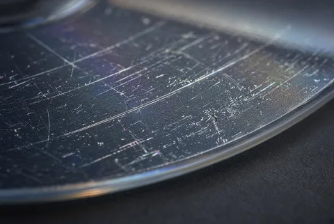 Extreme macro of a CD or DVD disc surface with several fine scratches and scuffs crossing the reflective read side