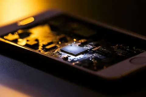 Smartphone circuit board with security chip highlighted by a narrow beam of light