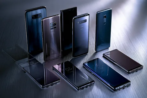 Several different smartphone brands and models laid out side by side on a dark workbench