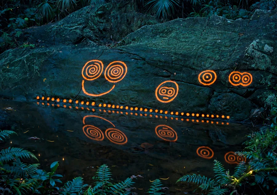 AI illustration, not a photograph: the real Reef Bay double spiral, faces and cup marks traced in warm orange light above a dark pool that reflects them
