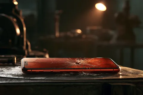 Smartphone lying on a workbench with a spider web cracked screen from impact damage