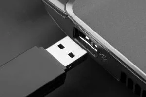A hand plugging a fast USB 3.0 flash drive into a laptop's USB port